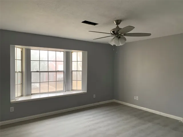 an empty room with a window and a fan