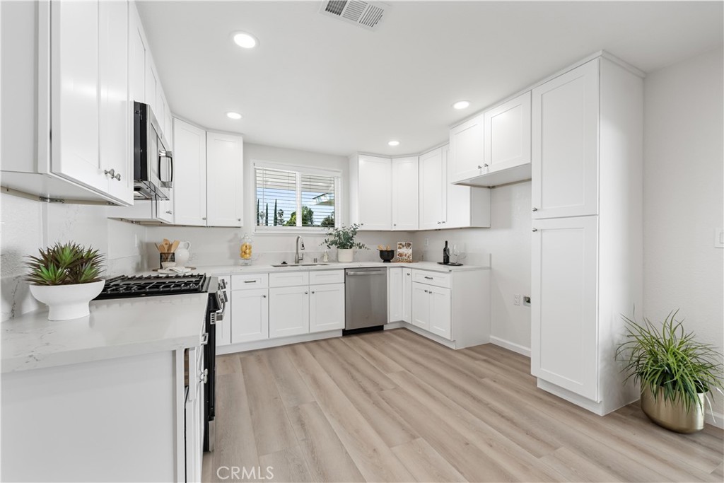 727 North Burney Street Rialto, CA 92376 - Photo 11 of 40 a kitchen with white cabinets white appliances sink and a potted plant