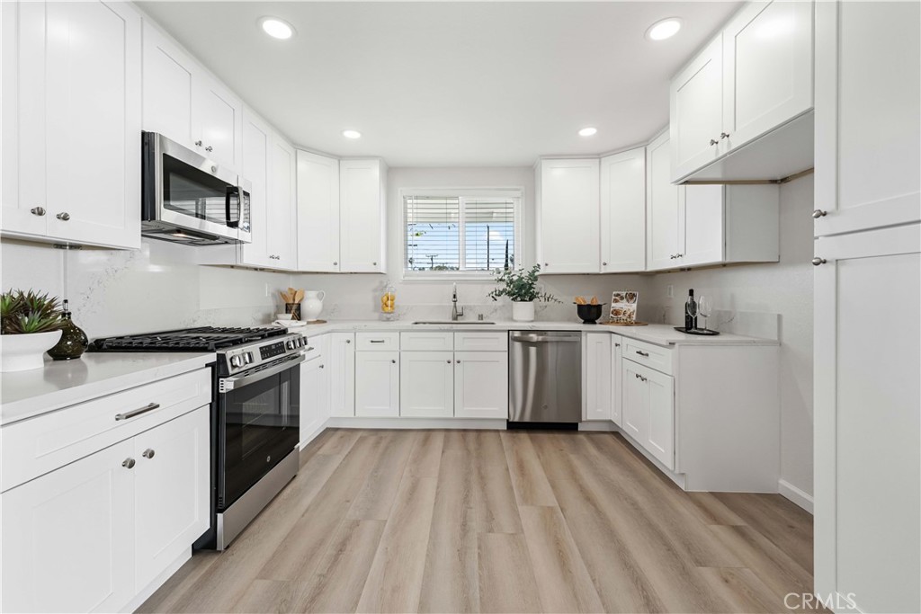 727 North Burney Street Rialto, CA 92376 - Photo 12 of 40 a kitchen with stainless steel appliances granite countertop white cabinets a sink dishwasher and a stove with wooden floor