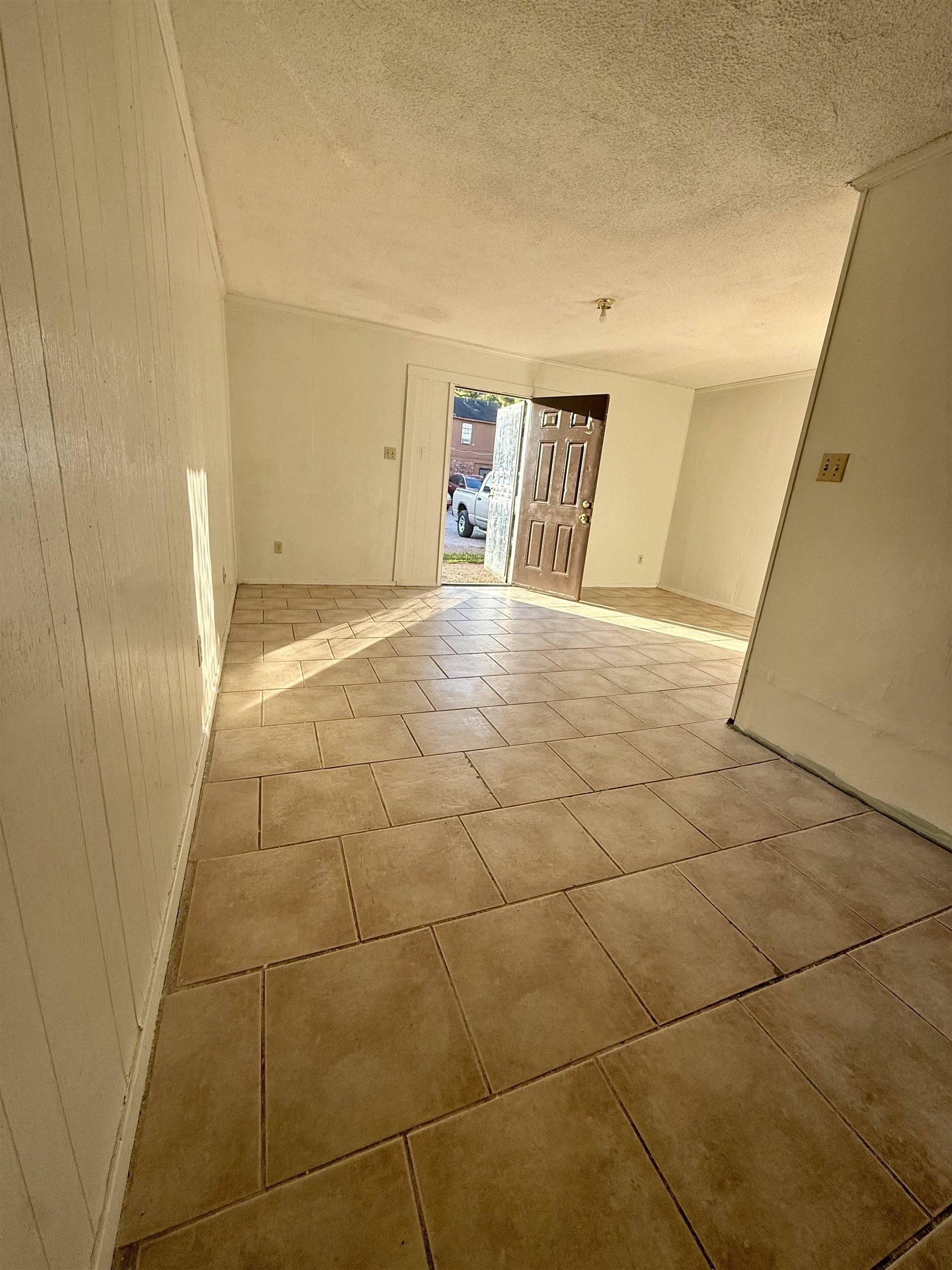 3091 Range Line Road Memphis, TN 38127 - Photo 2 of 13 Empty room with a textured ceiling, light tile patterned floors, and wooden walls