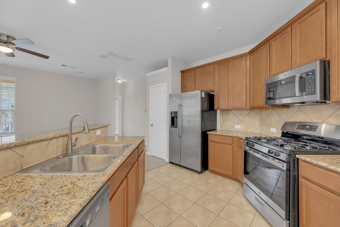 14815 Avery Ranch Boulevard, Unit 403/4B Austin, TX 78717 - Photo 14 of 38 a kitchen with a sink a refrigerator a microwave a stove and cabinets
