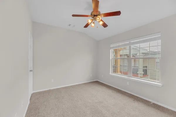 an empty room with windows and fan