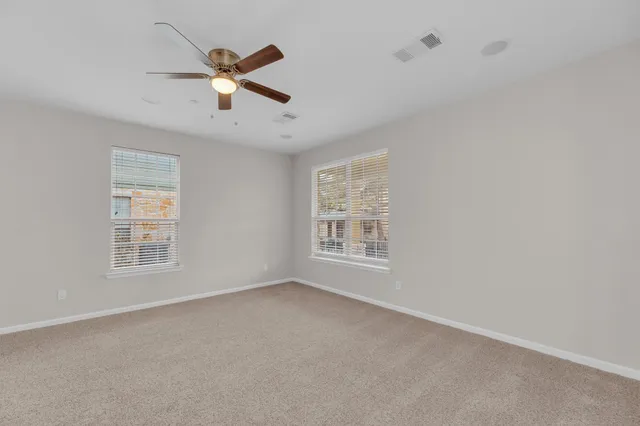 a view of an empty room with a ceiling fan and window