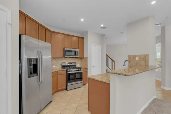 a kitchen with stainless steel appliances granite countertop a refrigerator and a stove top oven