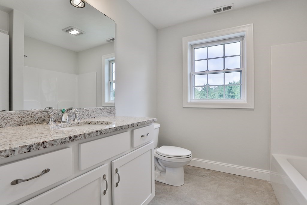 492 Northfield Road Lunenburg, MA 01462 - Photo 13 of 39 a bathroom with a granite countertop toilet a sink a mirror and a window
