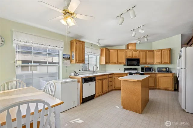 a kitchen with stainless steel appliances kitchen island granite countertop a stove top oven a sink a dining table and chairs