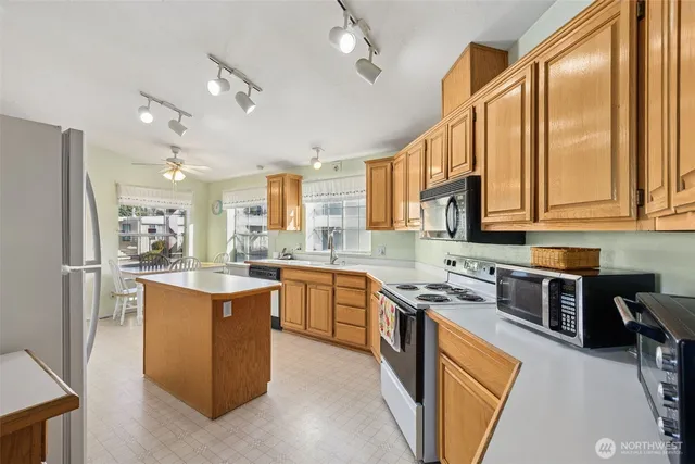 a kitchen with stainless steel appliances granite countertop a stove top oven a sink dishwasher a refrigerator and cabinets with wooden floor