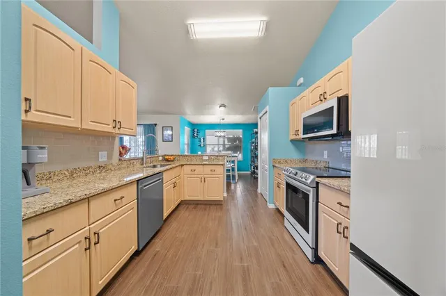 a large kitchen with granite countertop a stove top oven a sink a counter space and cabinets