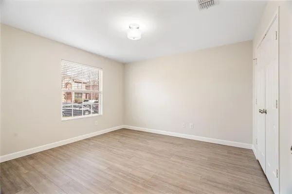 a view of an empty room with wooden floor and a window