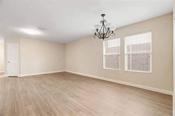 a view of an empty room with wooden floor and windows