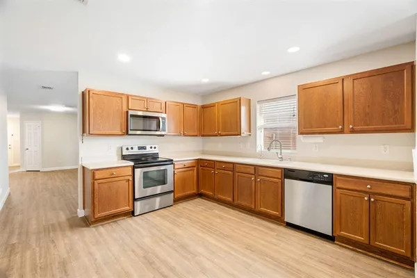 a kitchen with stainless steel appliances granite countertop a stove top oven a sink dishwasher and white cabinets with wooden floor