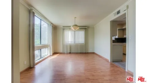 a view of an empty room with window and wooden floor
