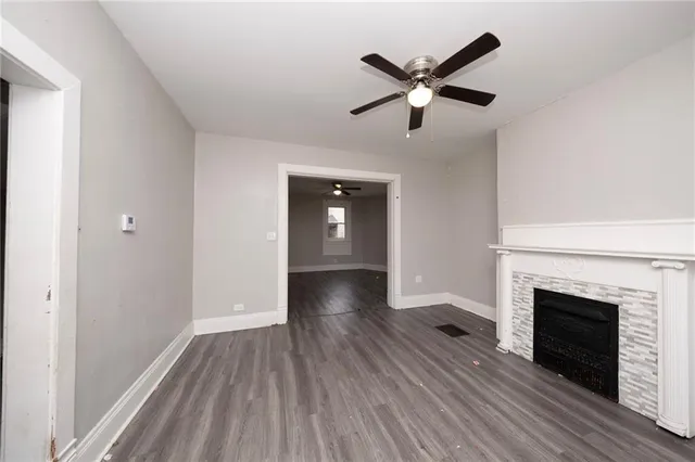 a view of empty room with wooden floor and fan