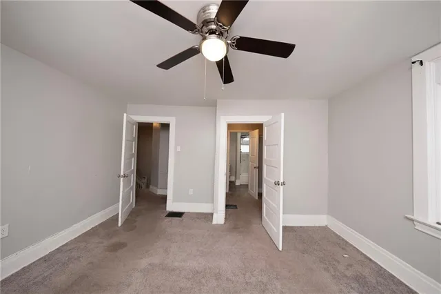 an empty room with ceiling fan and window