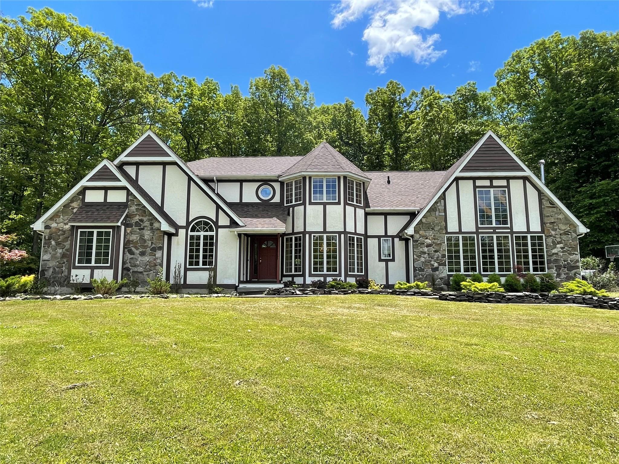 71 Saddleback Ridge Wallkill, NY 12589 - Photo 1 of 39 Tudor-style house with stone siding, stucco siding, a front yard, and roof with shingles