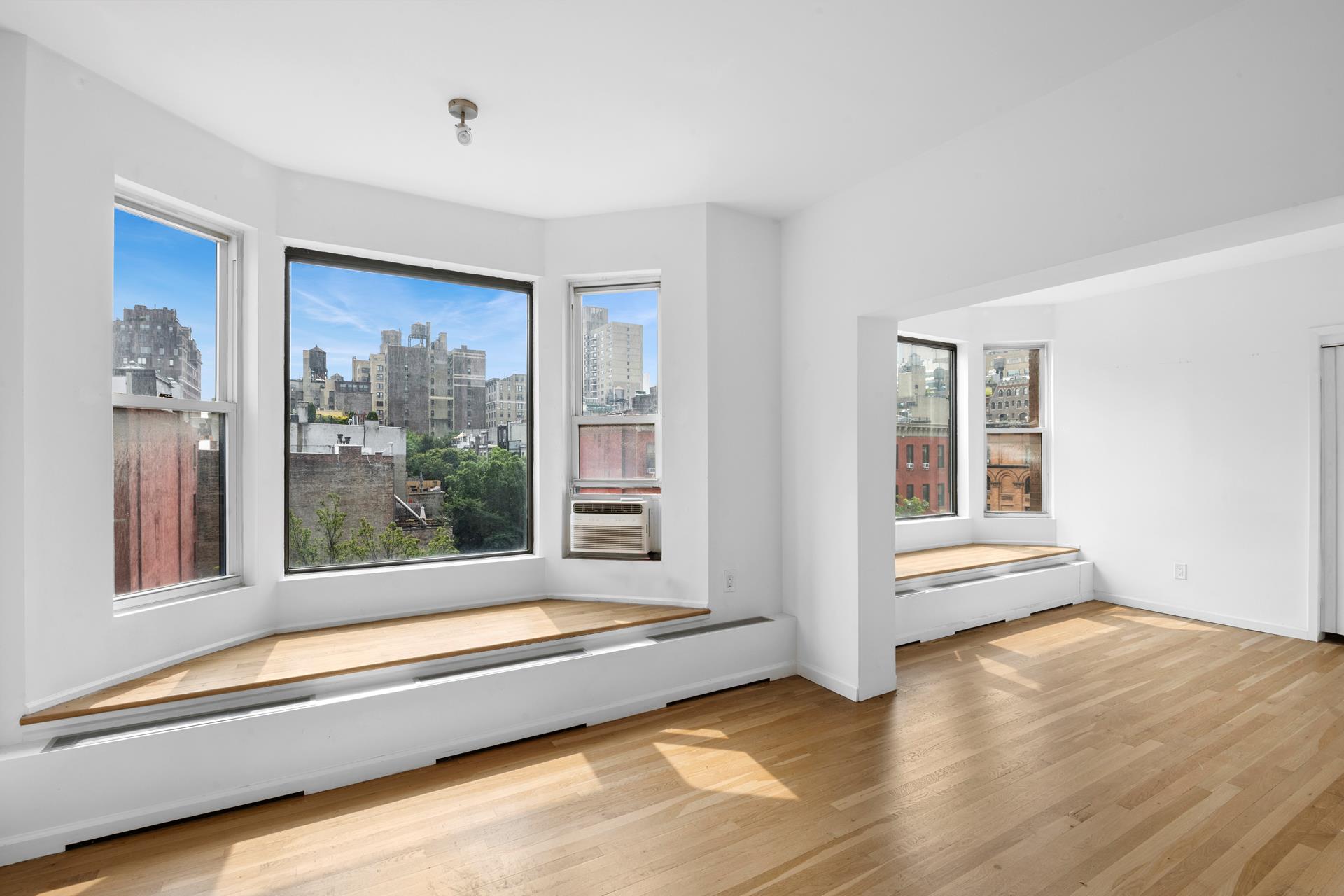 104 West 70th Street, Unit 5F Manhattan, NY 10023 - Photo 5 of 10 a view of an empty room with window wooden floor and a kitchen space