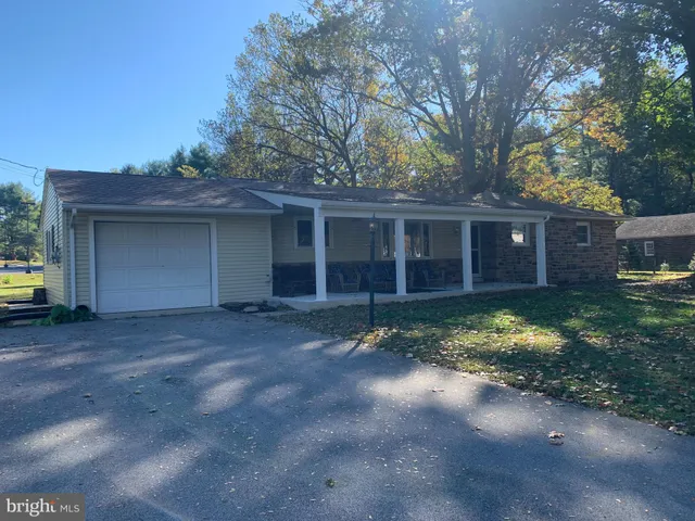a view of house with patio outdoor seating and covered with trees
