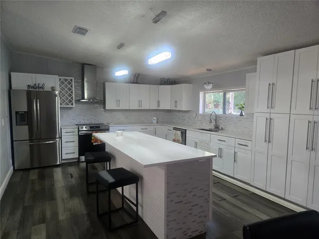 a kitchen with a sink a refrigerator and white cabinets