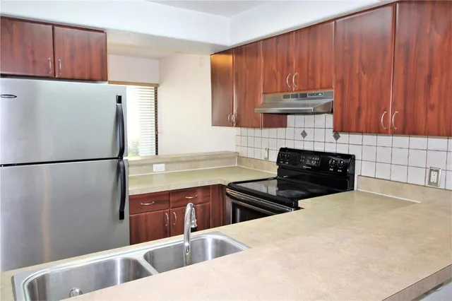 a kitchen with stainless steel appliances a sink a stove a refrigerator a sink and cabinets