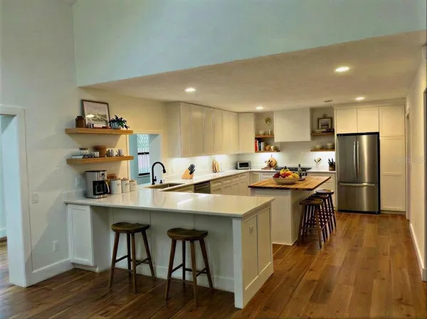 a kitchen with kitchen island granite countertop a sink and refrigerator