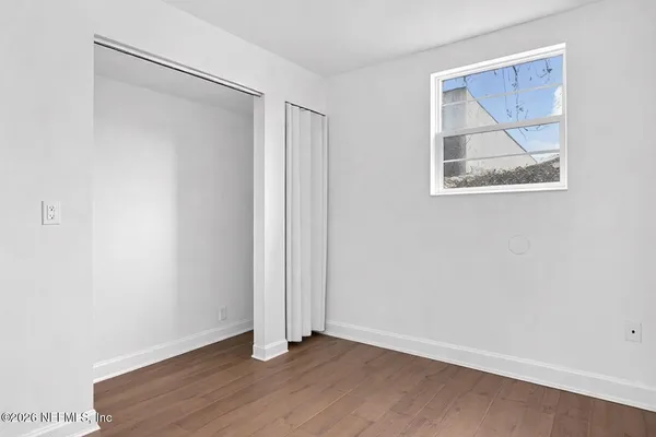 an empty room with a window and wooden floor