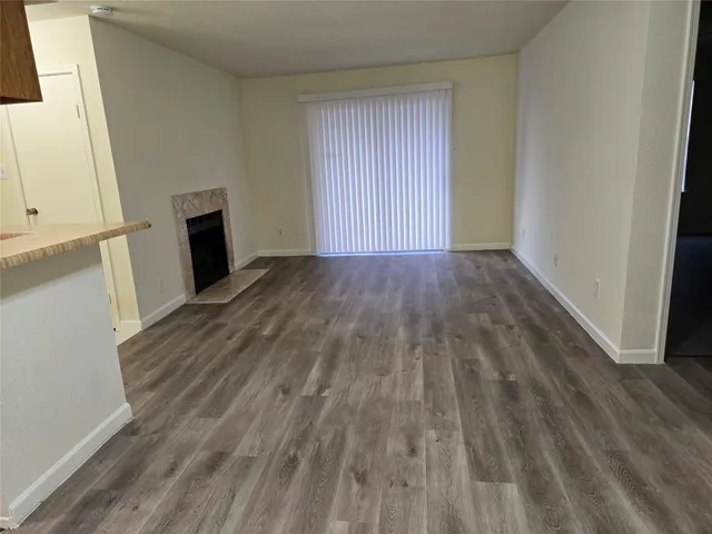 a view of empty room with wooden floor and fireplace