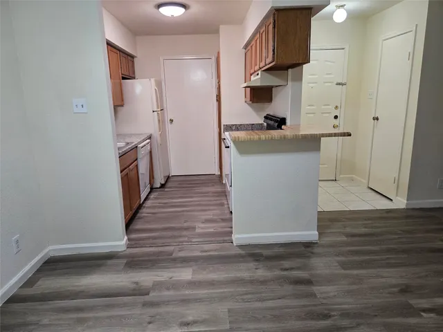 a kitchen view with wooden floor and electronic appliances