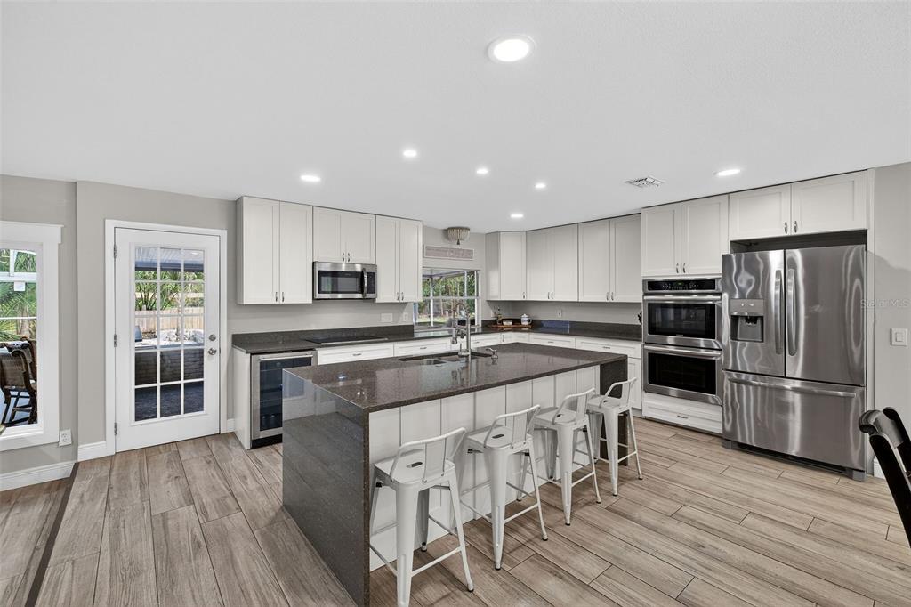 182 Parsons Road Longwood, FL 32779 - Photo 7 of 54 a large kitchen with kitchen island wooden floors and stainless steel appliances