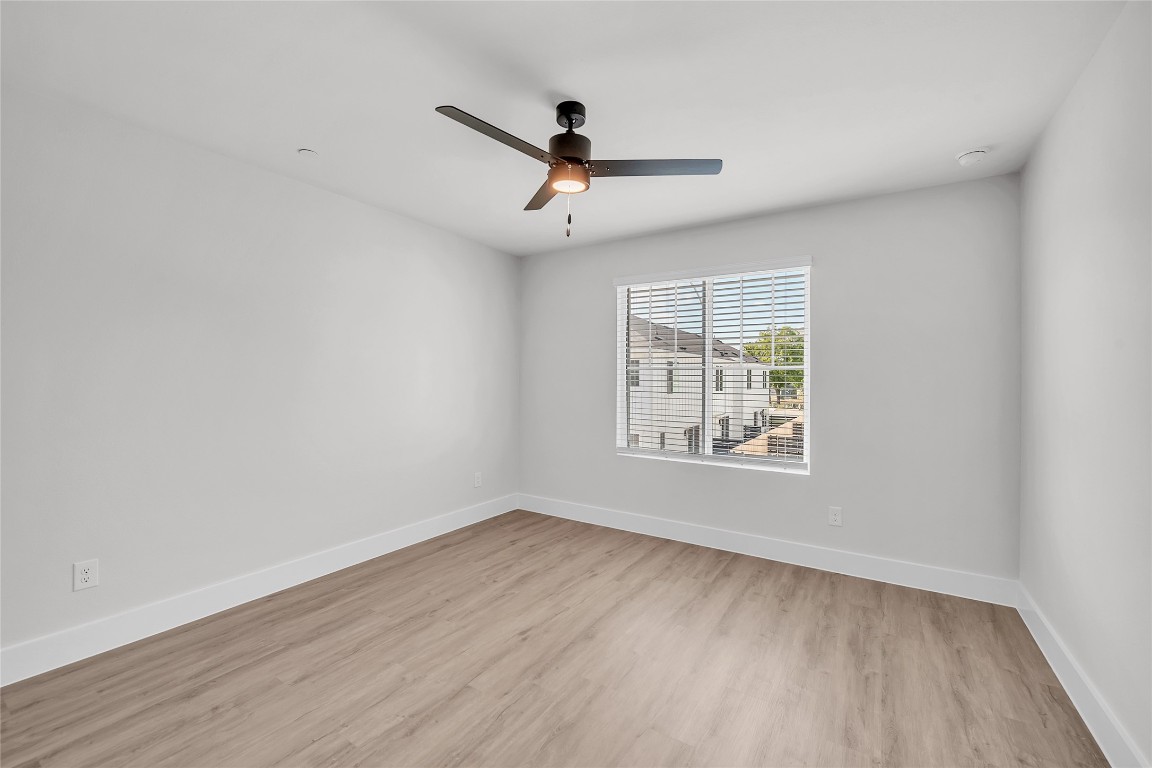 9317 Curious Squirrel Street Austin, TX 78744 - Photo 14 of 26 an empty room with wooden floor ceiling fan and windows