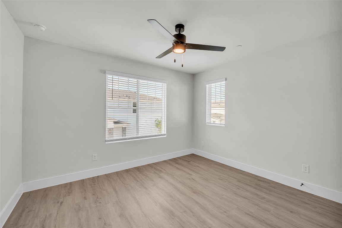 9317 Curious Squirrel Street Austin, TX 78744 - Photo 16 of 26 an empty room with wooden floor ceiling fan and windows