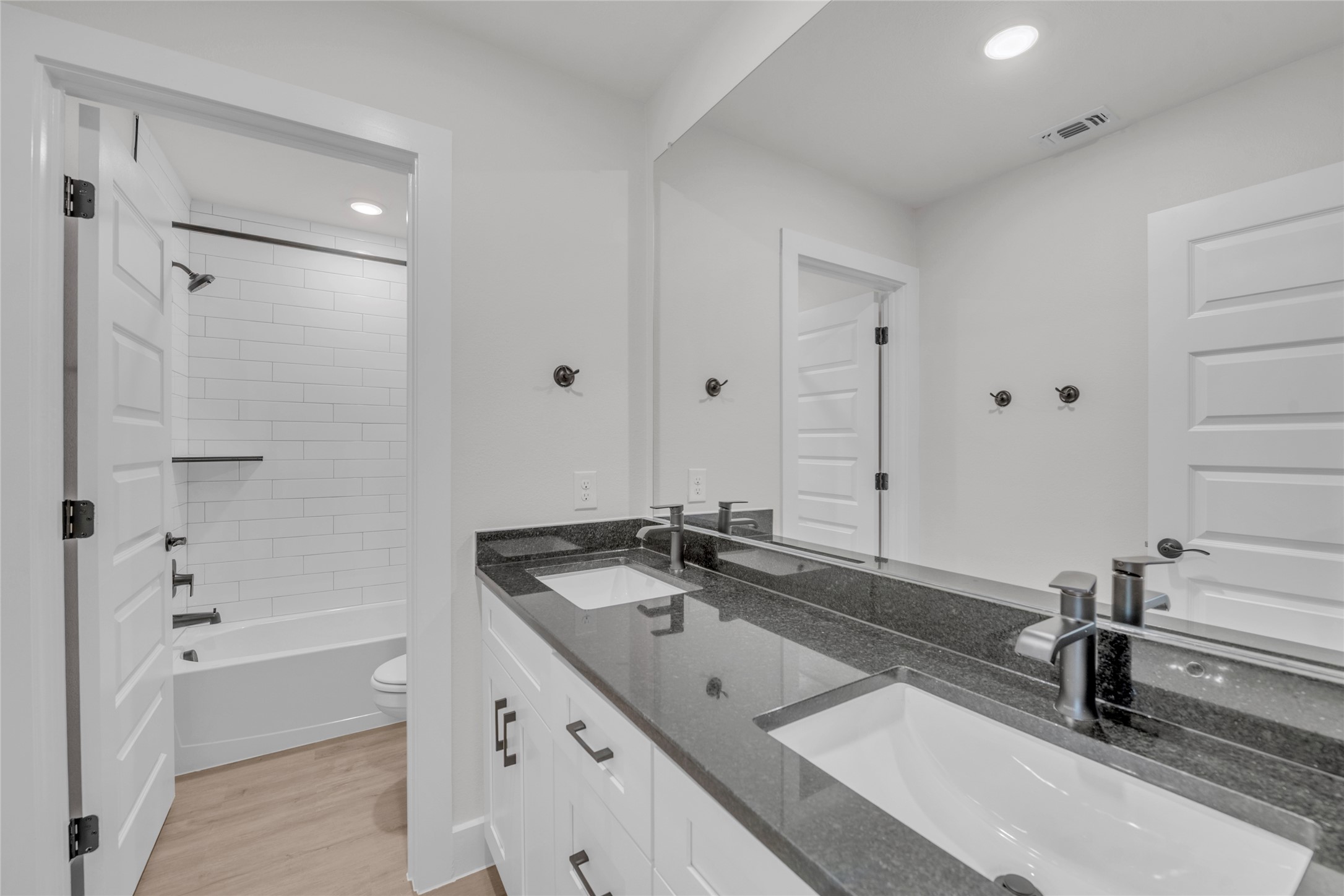 9317 Curious Squirrel Street Austin, TX 78744 - Photo 18 of 26 Bathroom featuring double vanity, tub / shower combination, recessed lighting, and light wood-style flooring