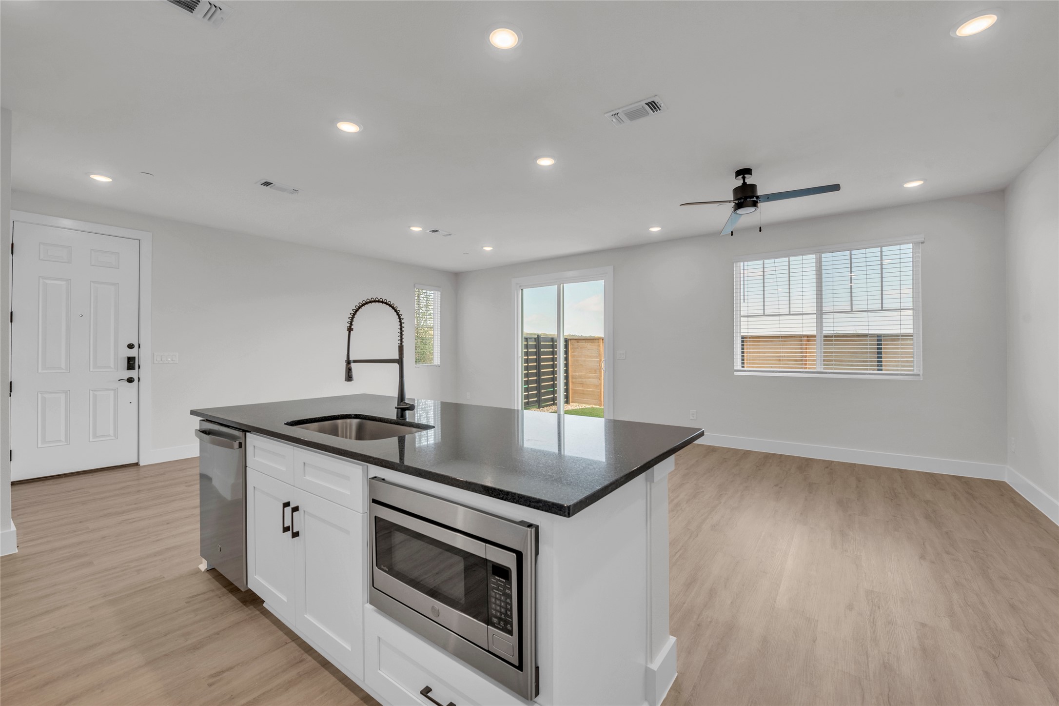 9317 Curious Squirrel Street Austin, TX 78744 - Photo 26 of 26 Kitchen featuring open floor plan, appliances with stainless steel finishes, a center island with sink, white cabinets, and recessed lighting