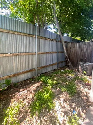 a view of backyard with wooden fence and a large tree