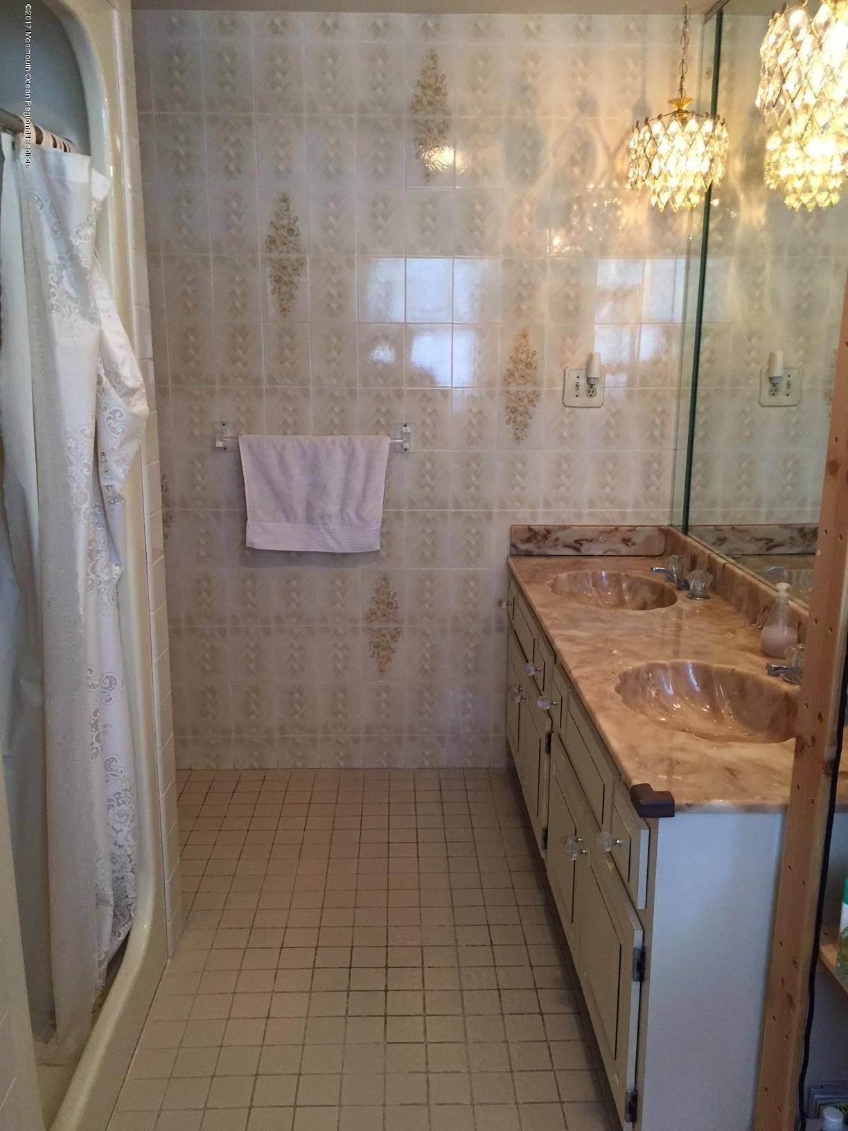 176 Stone Hill Road Colts Neck, NJ 07722 - Photo 21 of 26 a bathroom with a granite countertop shower a sink and a mirror