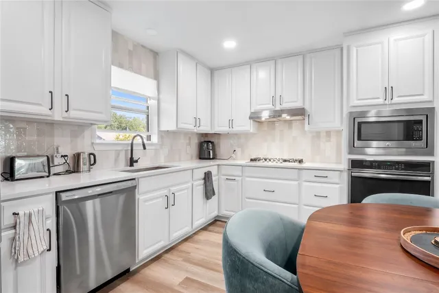 a kitchen with granite countertop white cabinets sink and stainless steel appliances
