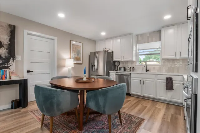 a kitchen with stainless steel appliances granite countertop a sink a stove a refrigerator with a dining table and chairs