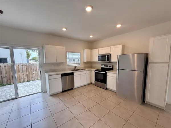 a kitchen with granite countertop a refrigerator and a stove top oven