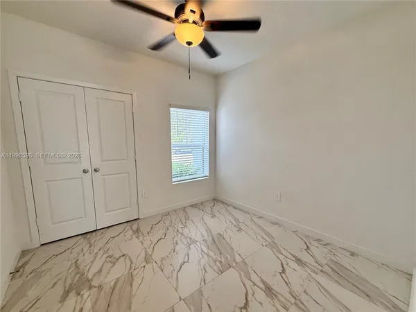 a view of empty room with window and chandelier fan