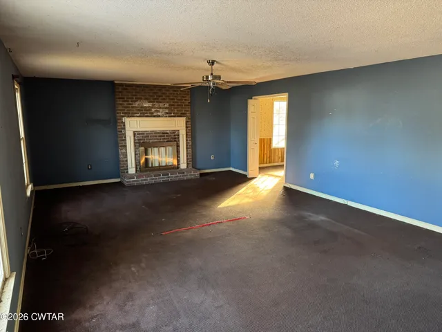 an empty room with windows and fireplace