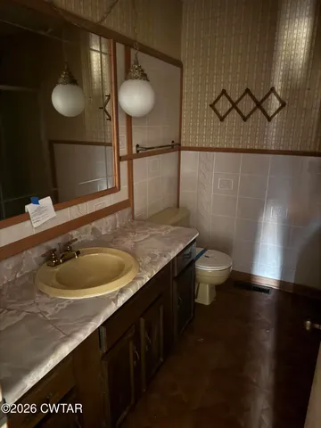 a bathroom with a granite countertop sink a toilet and a mirror