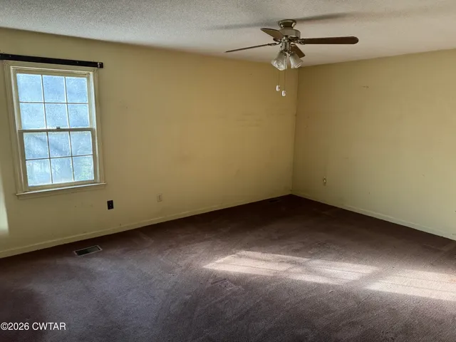 an empty room with windows and fan