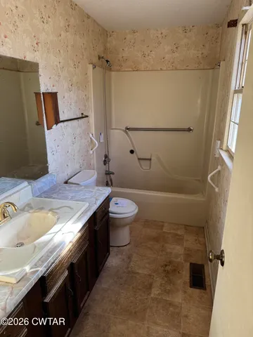 a bathroom with a granite countertop sink a toilet and shower