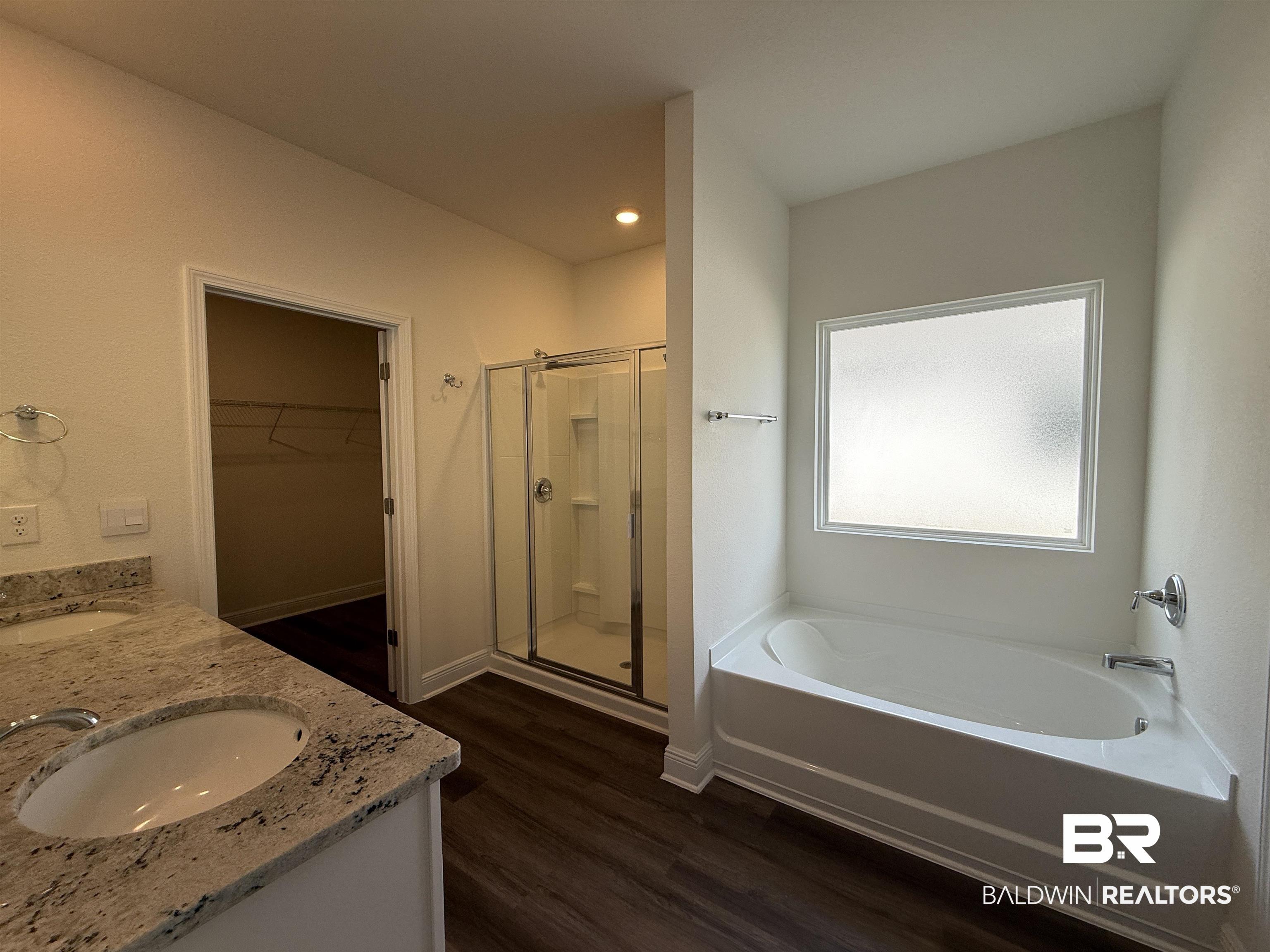 11442 Genuine Risk Circle Daphne, AL 36526 - Photo 10 of 21 Full bath featuring a walk in closet, a stall shower, double vanity, a garden tub, and dark wood-style floors