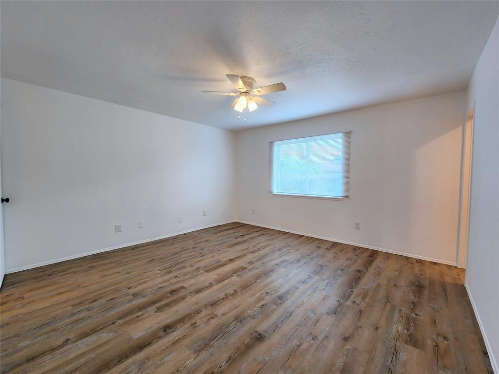 5541 Ragan Drive The Colony, TX 75056 - Photo 17 of 23 an empty room with wooden floor chandelier fan and windows