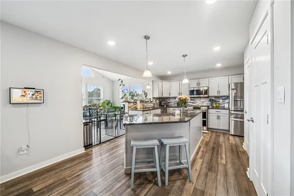 a kitchen with stainless steel appliances a dining table chairs stove and cabinets