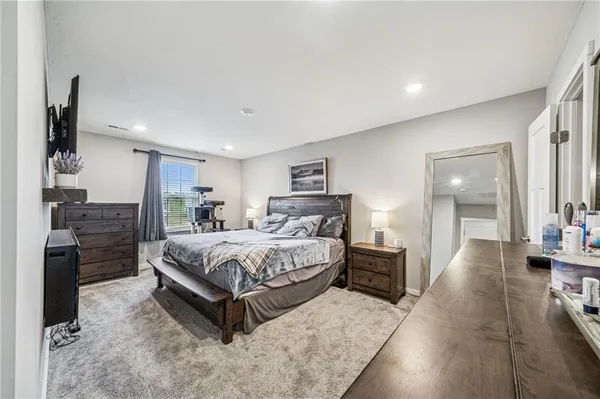 a spacious bedroom with a bed and a flat screen tv