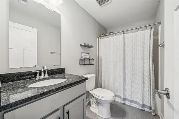 a bathroom with a granite countertop sink toilet and shower