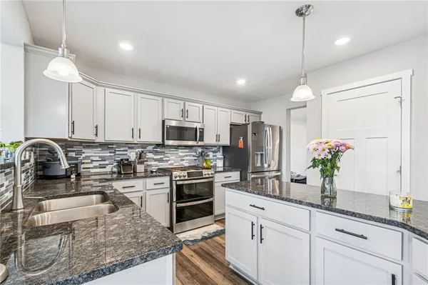 a kitchen with stainless steel appliances granite countertop a sink a stove and a refrigerator