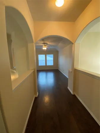 an empty room with wooden floor chandelier and windows