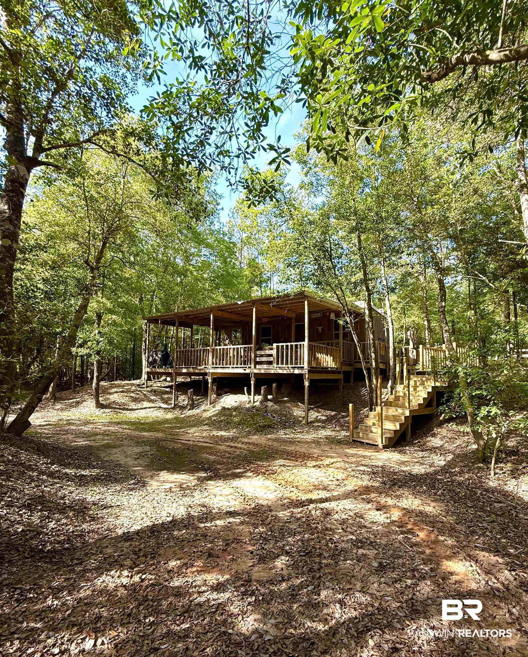 1 Mason Ferry Road Citronelle, AL 36522 - Photo 2 of 40 Raised wooden cabin featuring an expansive front porch with railing, exterior wood siding, and surrounding mature trees
